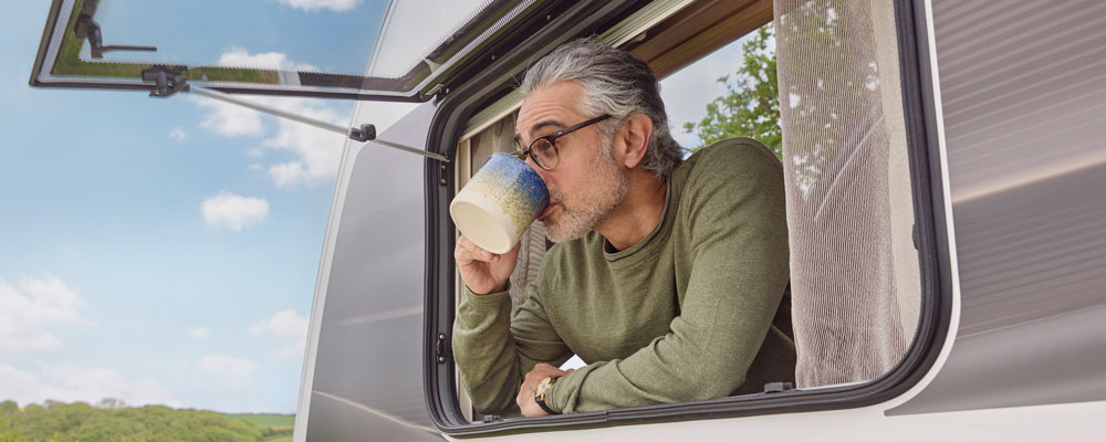 What Do I Need to Take on a Caravan Holiday? Man Drinking Coffee in Caravan